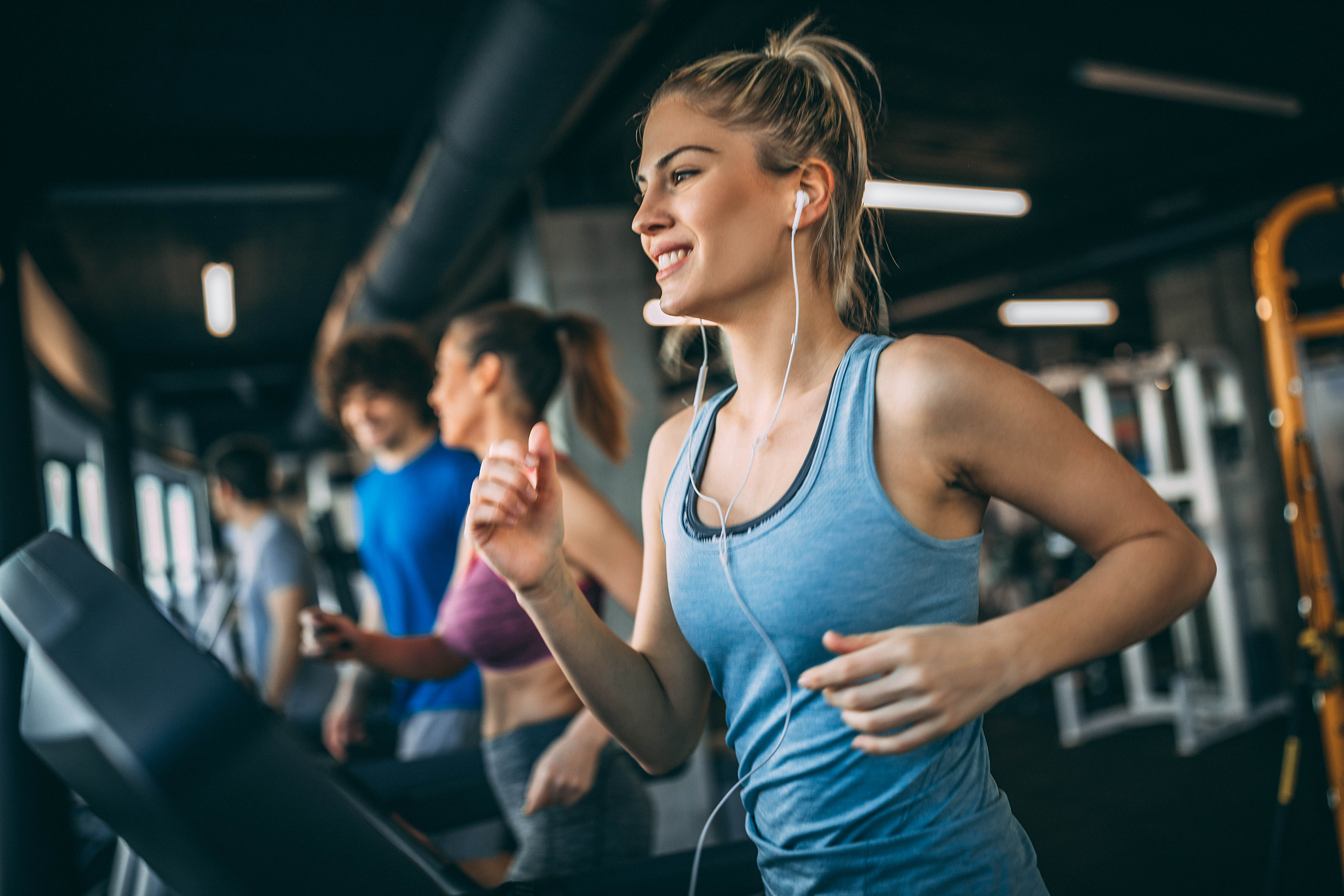 Young blonde woman running on a treadmill in a gym